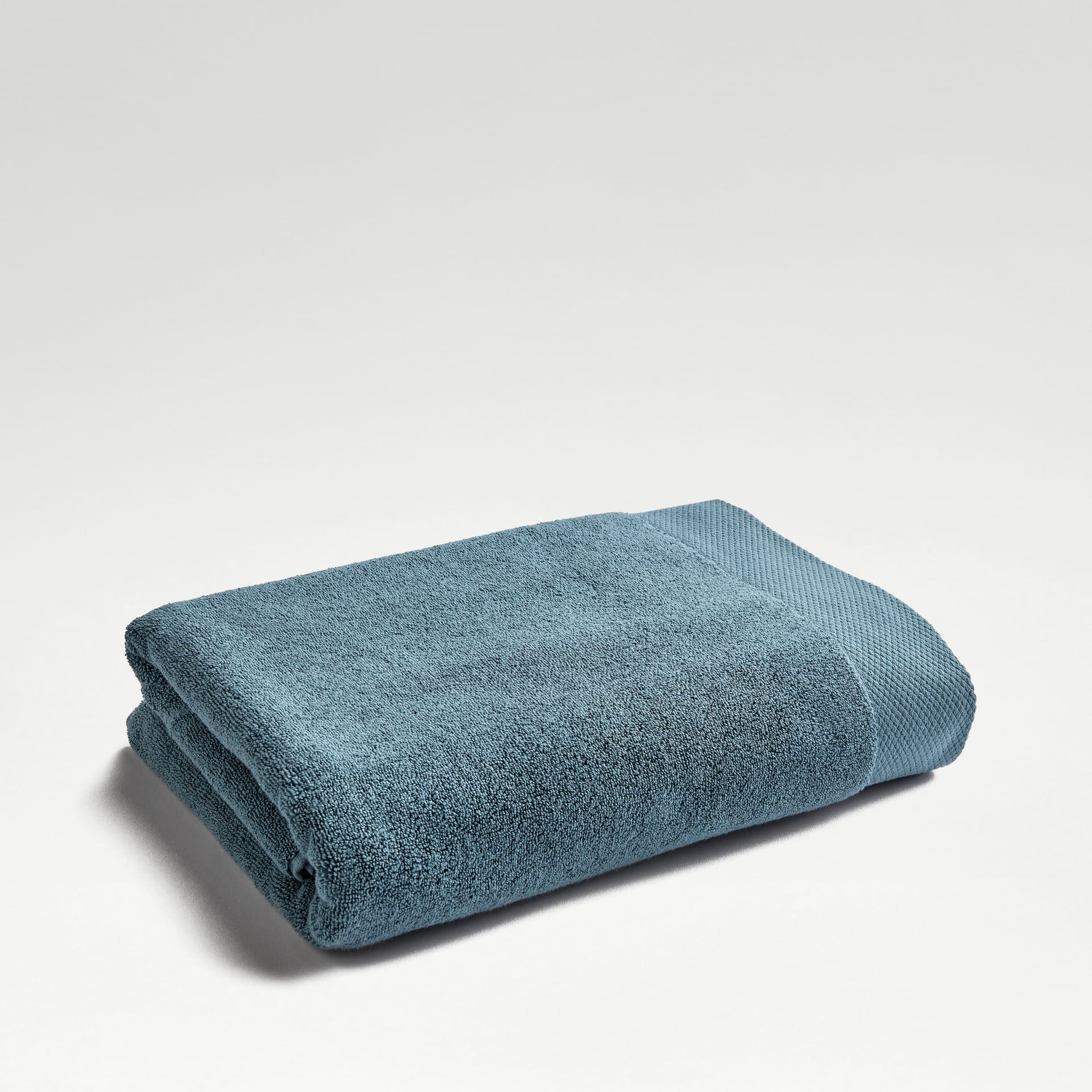 A thick white bath towel in long-staple Turkish cotton, folded.
